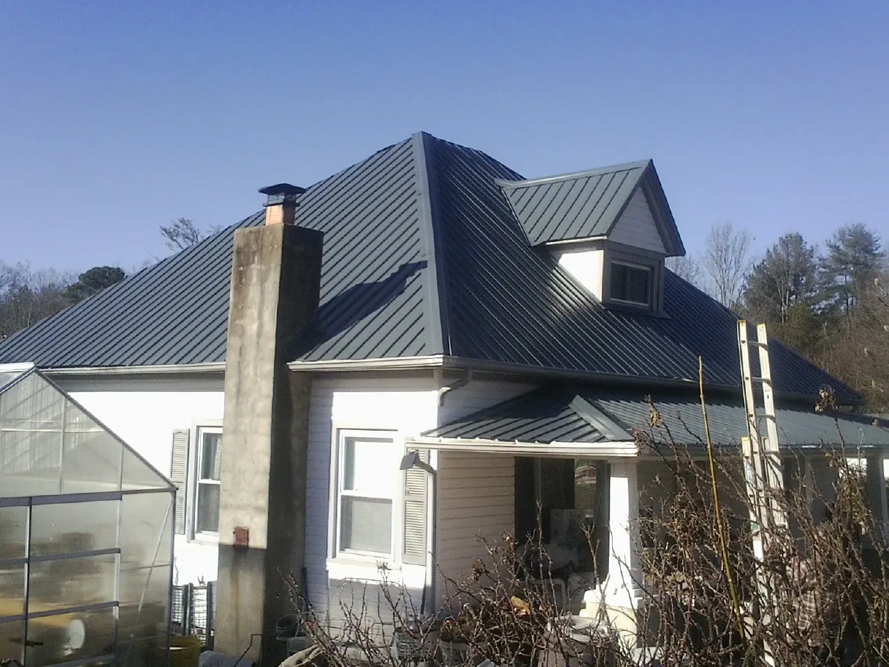 Dark blue standing seam metal roof on a white farmhouse with dormer — Slate & Tile Roof Repair by Roofing Brothers in Millry