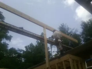 Carpenter setting a ridge beam over a new addition frame — Ice Dam Removal by Roofing Brothers in Millry