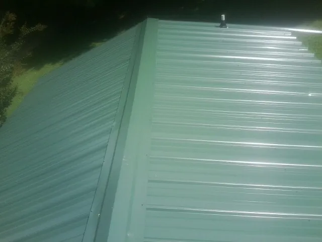 New green metal panels meeting at the ridge of a roof — Flat Roof Repair work by our crew in Millry