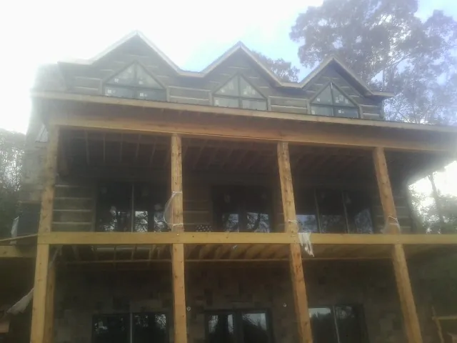 Dormers and porch framing on a large log home under construction — Roof Coating work by our crew in Millry