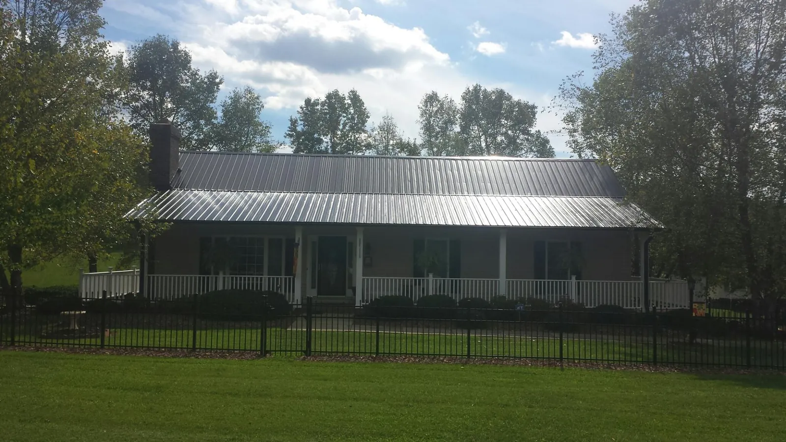Gray metal roof on a brick ranch with a full width front porch — Gutter Guard Installation work by our crew in Millry