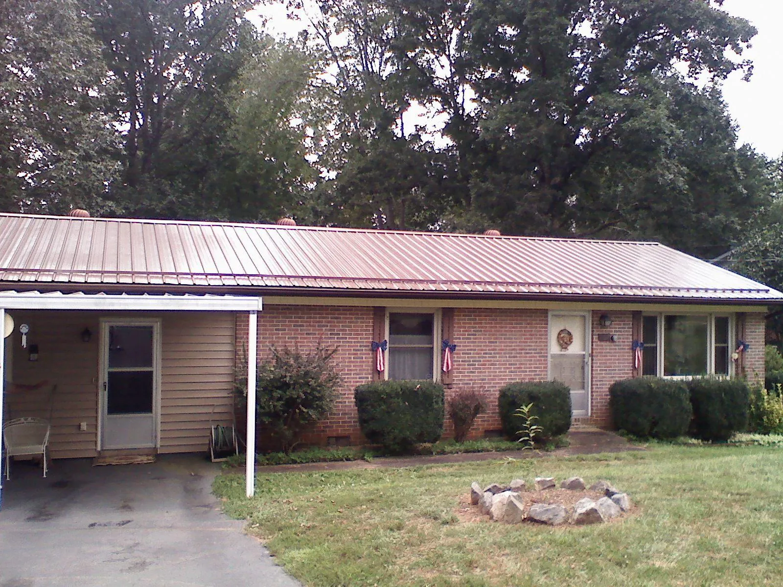 Bronze metal roof and carport on a brick ranch home — Roof Repair work by our crew in Millry
